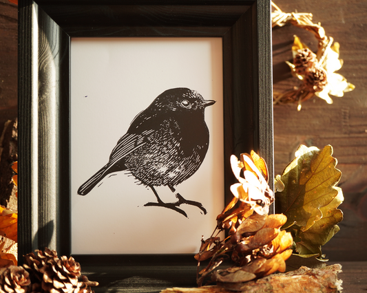 Linocut print of a robin bird surrounded by autumn leaves.