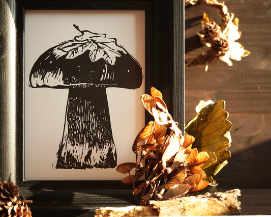Linocut print of a boletus surrounded by autumn leaves.