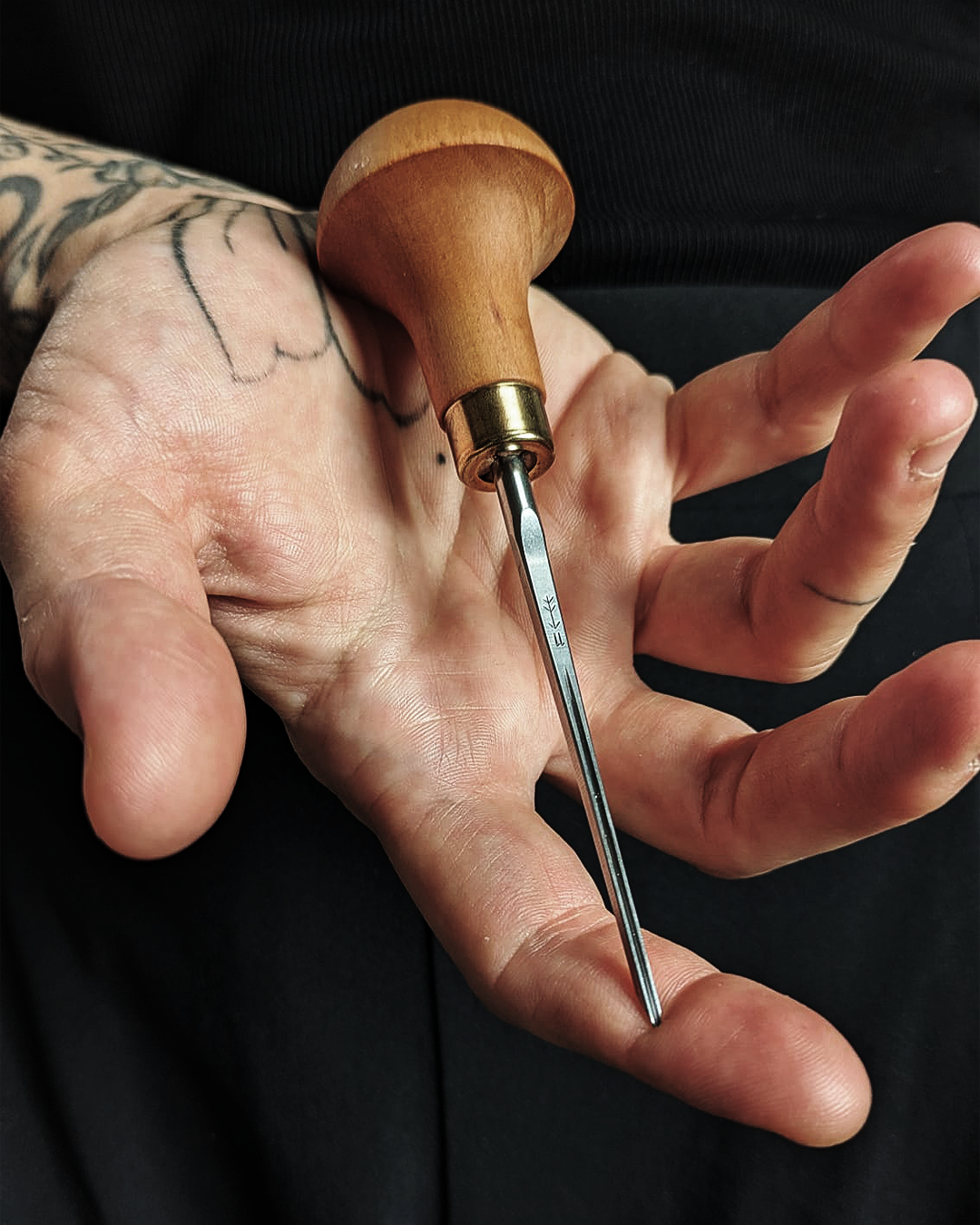 Hand holding a linocut gouge, tool of slow art and forest-inspired engraving.