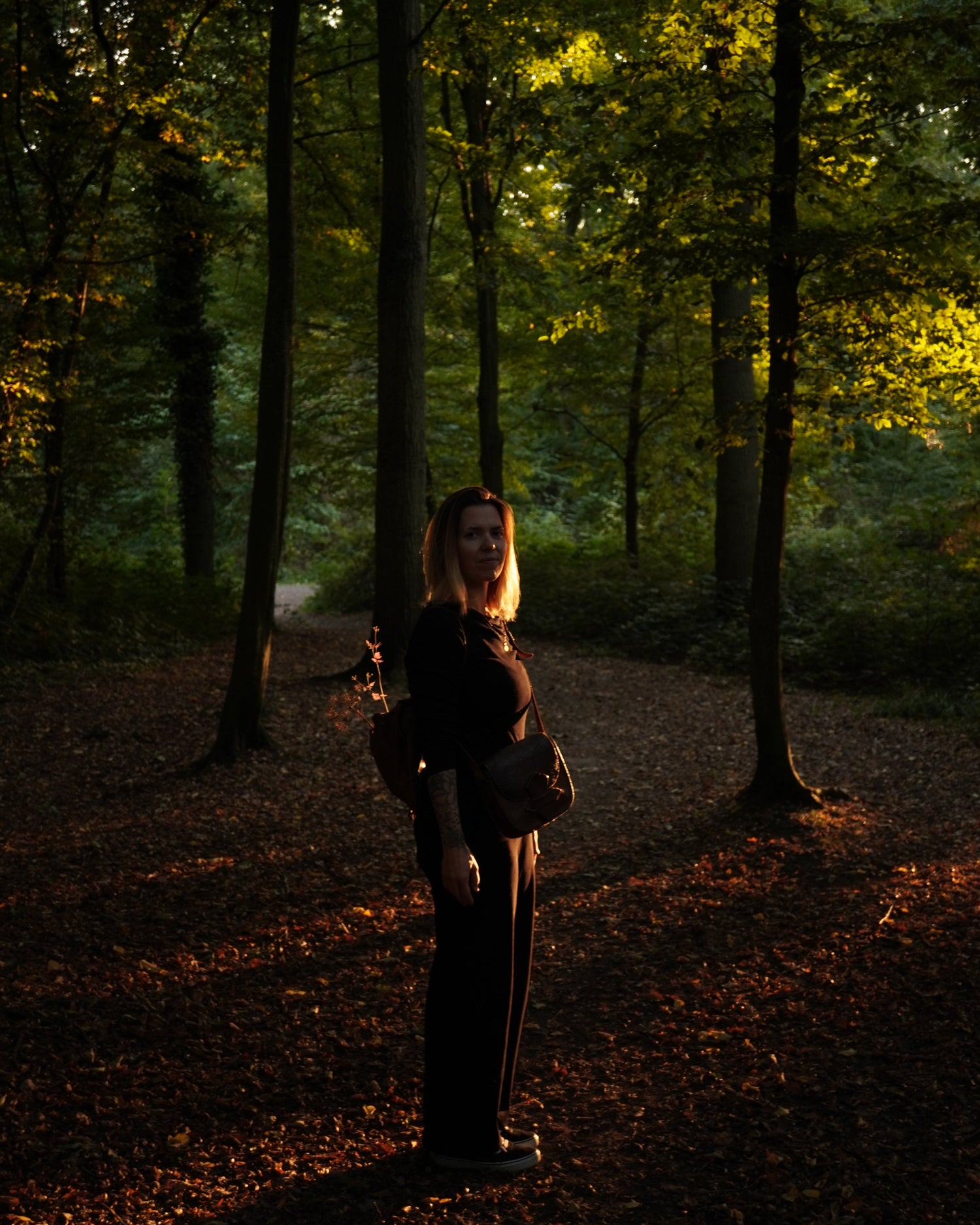 Artist Hazel Lithwood standing in a sunlit forest, slow art inspired by nature and shadows.