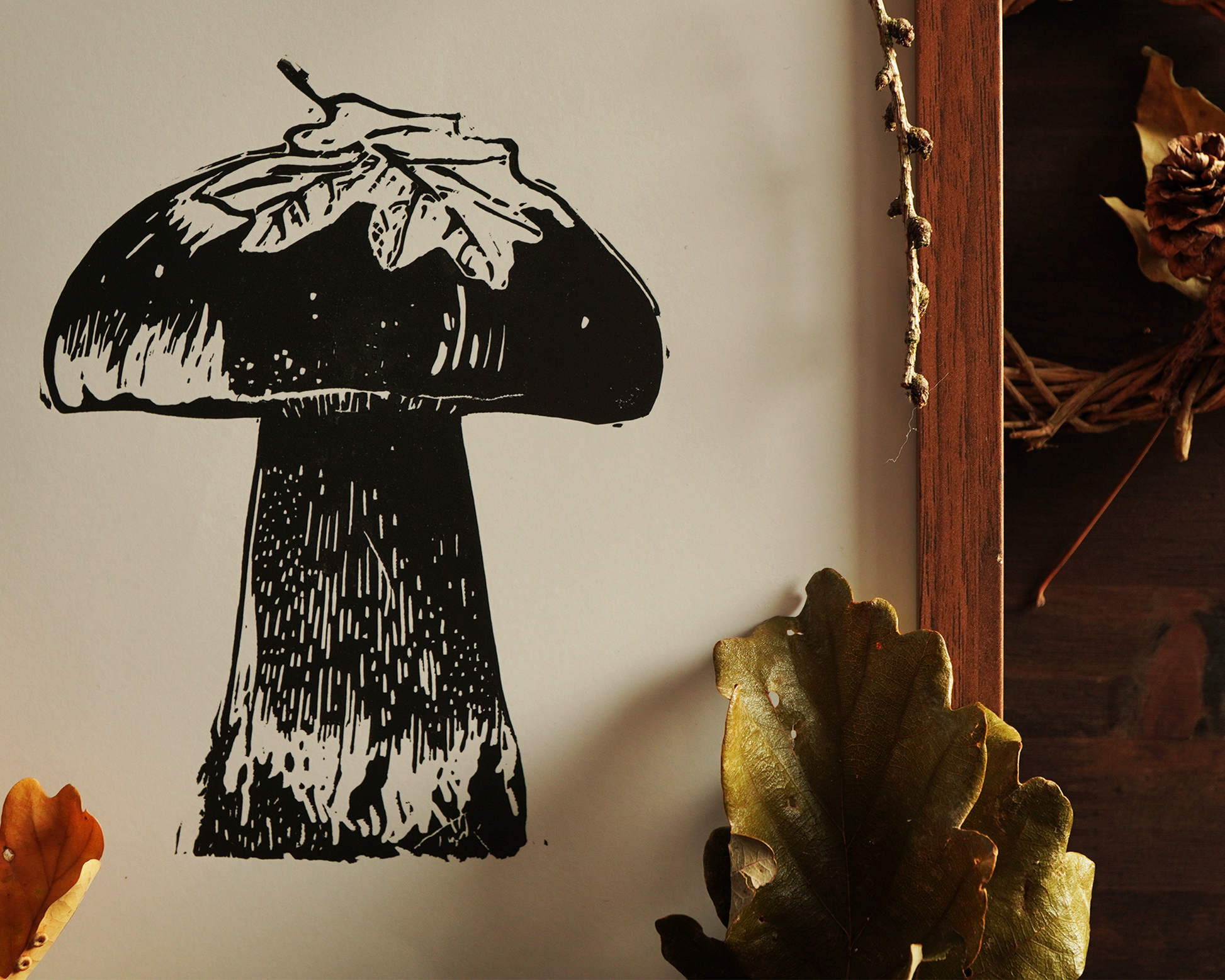 Linocut print of a boletus surrounded by autumn leaves.