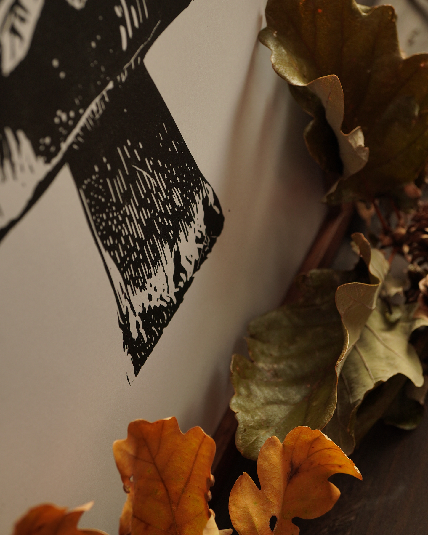 Zoom in a linocut print of a boletus surrounded by autumn leaves.