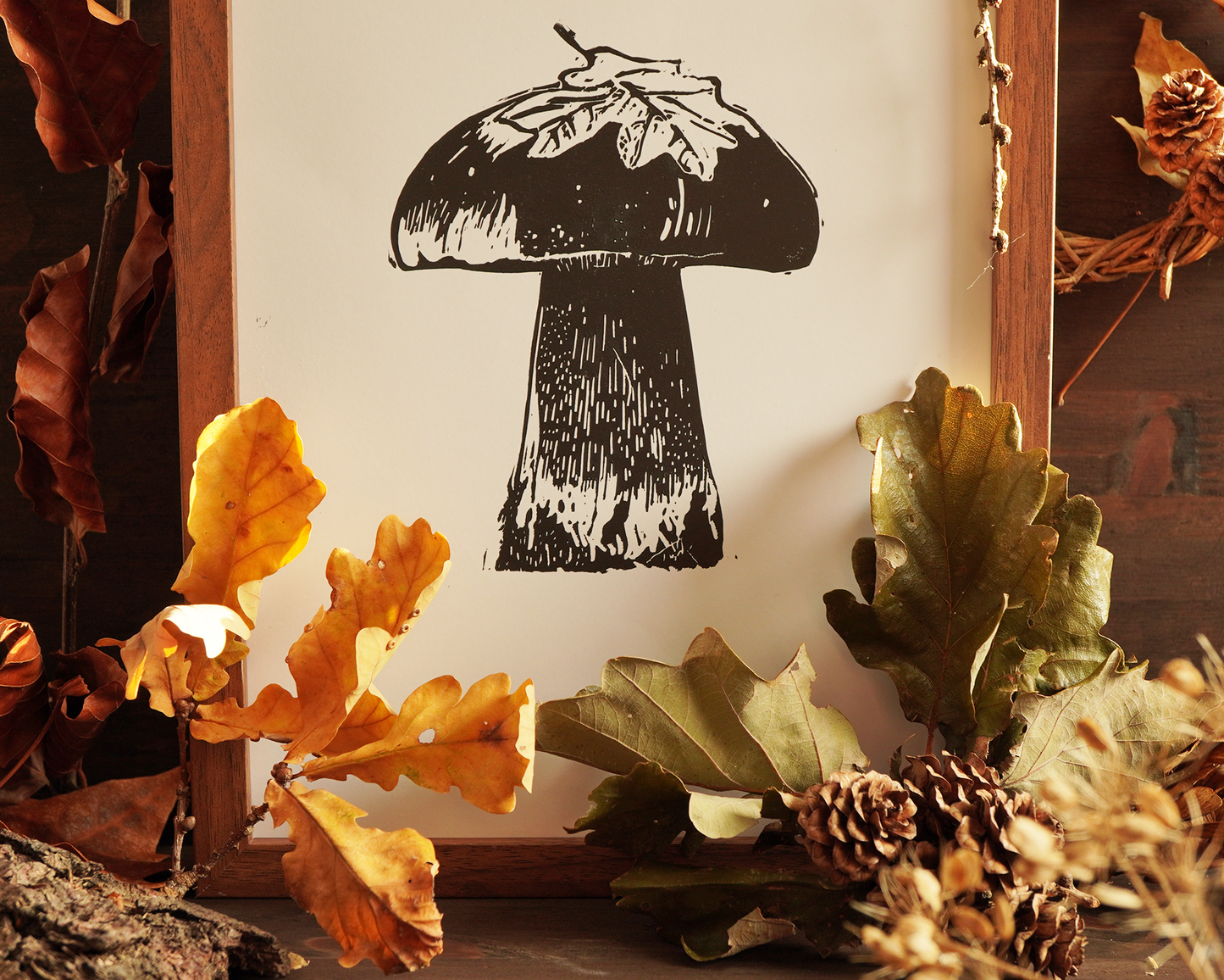 Linocut print of a boletus surrounded by autumn leaves.