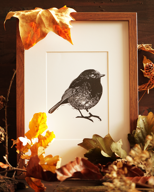 Linocut print of a robin bird surrounded by autumn leaves.