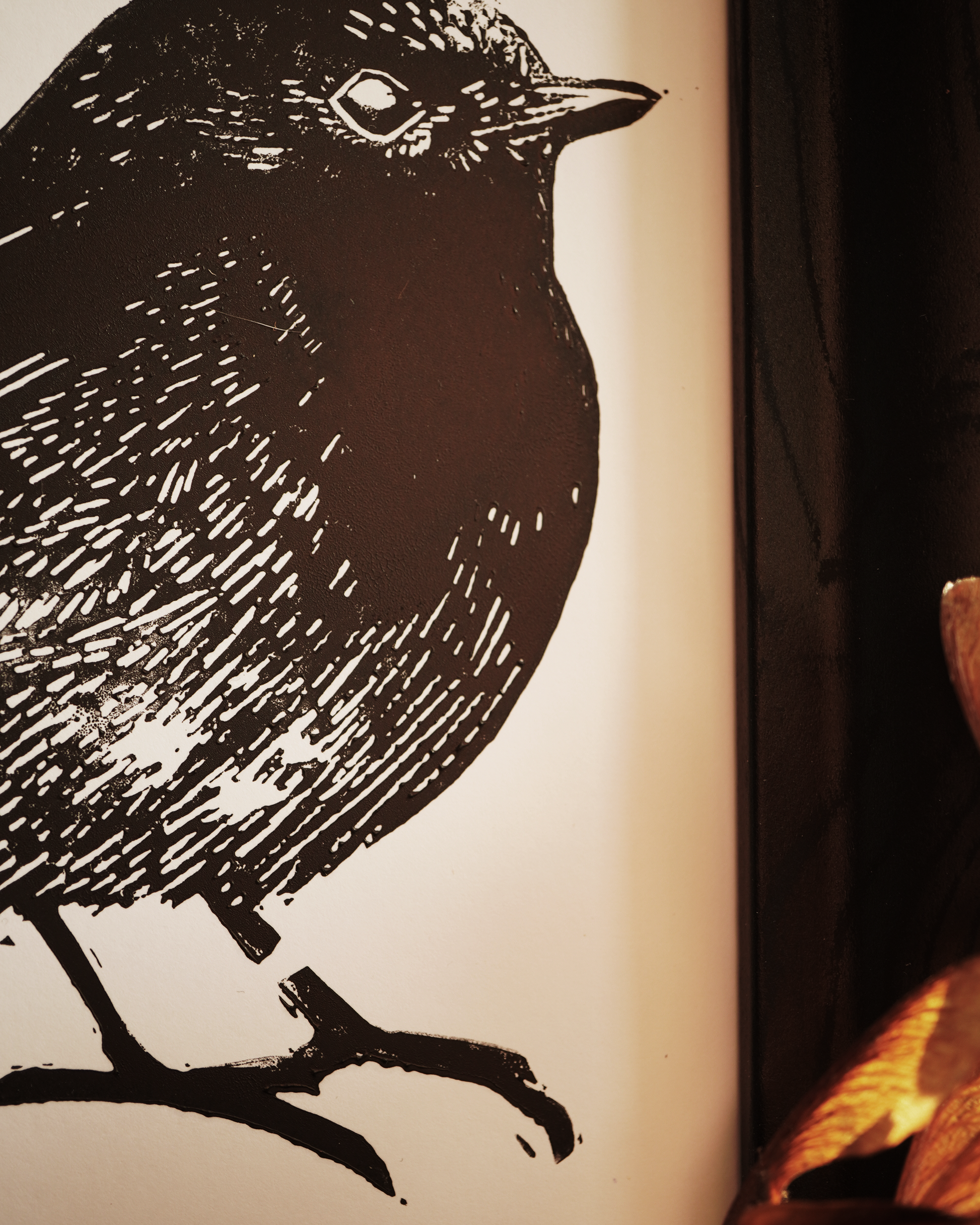 Zoom in a linocut print of a robin bird surrounded by autumn leaves.