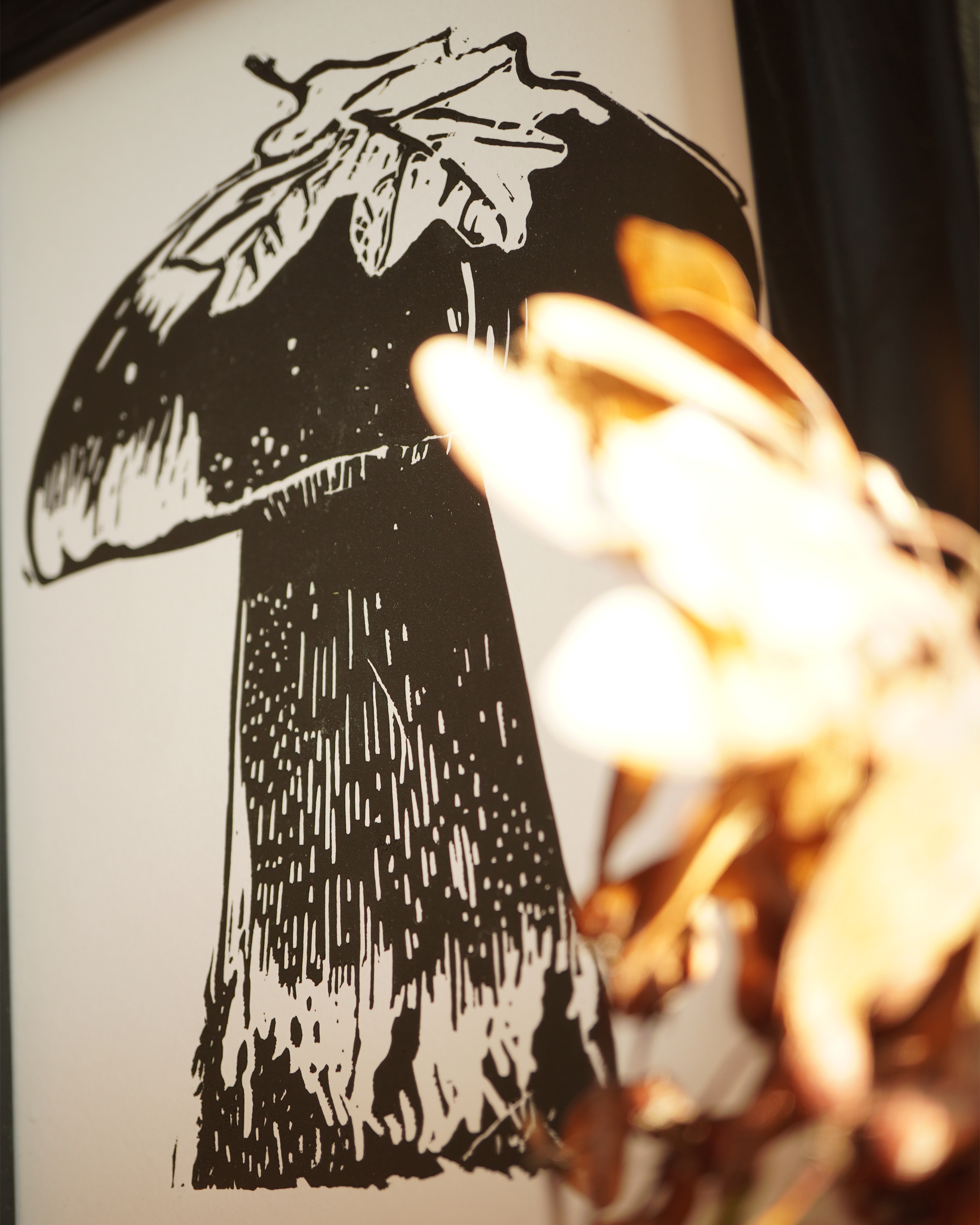 Linocut print of a boletus surrounded by autumn leaves.